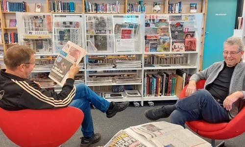 To menn som les aviser i biblioteket på Nærbø