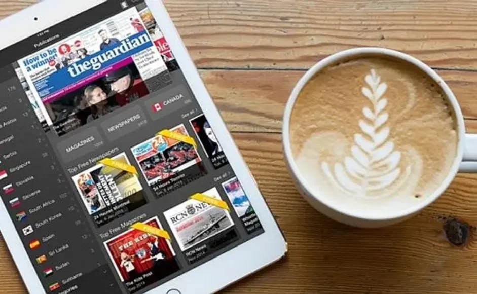 Digital avis på nettbrett og kaffikopp ved sida av